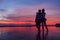 Two girlfriends hugging up and enjoying a rose/pink sunset sky on the sea beach on the Samui Island,Thailand. Calm warm countries