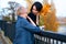 Two girlfriends talking and posing in autumn city park. Beautiful adult woman, blond and brunette