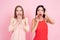 Two girls acting surprised on pink background celebrating women`s day March 8.
