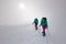 two girls with a backpack and snowshoes walk in the snow during a snow storm