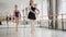 Two girls ballet dancers are practising dancing on tiptoes with their experienced teacher during ballet lesson in studio