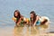 Two girls in bikini play with a water guns