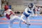 Two girls in blue and red Taekwondo equipment fight in doyang in Taekwondo competitions