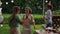 Two girls and a boy in a birthday hat have a fan around the set table. Cheerful teenagers dancing at a birthday party