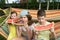 Two girls and a boy sit in a hammock and eat a red watermelon