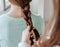 Two girls braid their hair at the window. Woman makes a braid to her friend. Hair weaving hairstyles. Girlfriend braids her hands