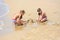 Two girls build sand castles on the seashore