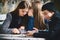 Two girls bullying a worried colleague that is sitting