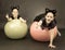 Two girls in cat costumes on fitness balls on black background i