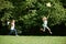 Two Girls Chasing Butterflies In Summer Field