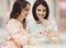 Two Girls Chatting in Cafeteria with Cups of Coffee.