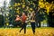 Two girls cheerfully spend time in the autumn park.