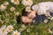 Two girls with closed eyes in dark blue and white dresses in sunny day lying down  and sleeping in chamomile field