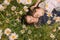 Two girls with closed eyes in dark blue and white dresses in sunny day lying down  and sleeping in chamomile field