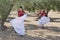 Two girls dance flamenco in an olive grove making a symmetrical movement