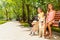 Two girls with dogs sitting in park on bench