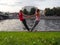 Two girls doing couple yoga asana on the river bank in a city park