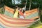 Two girls eating watermelon and joking, outdoors, sitting on a hammock