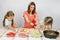 Two girls enthusiastically watched as mum pours ketchup basis for pizza