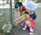 Two girls feed rabbits leaves in an aviary