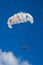 Two girls flying on a parachute behind a boat on a summer holiday by the sea .