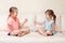 Two girls friends playing rock paper scissors hand game. Caucasian children sitting on a couch playing together. Interesting
