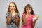 Two girls are funny eating bread, pushing food into your mouth with your fingers