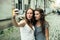 Two girls girlfriend take a selfie on smartphone outdoors in the old town.