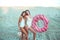 Two girls girlfriends standing sand with inflatable circle, beautiful women beach white bodysuit. Holidays sea on ocean