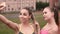 Two girls grimacing when taking photo with phone. Young fitness women posing when taking photo in park.