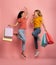 Two girls are happy after shopping. Joyful expression. Shop concept. Pink background