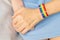 Two girls are holding hands, on one hand there is LGBT bracelet.