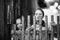 Two girls little sisters look out from behind a wooden fence in village.