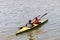 Two girls with oars are rowing synchronously on a kayak on the river. Amateur rafting