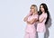 Two girls in pink scrubs and disposable gloves posing isolated on white. Medical staff, cosmetologist, tattoo artist. Close up