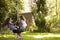 Two Girls Playing Together On Tire Swing In Garden