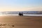 Two girls riding bicycles in the beach sand at the sunset.