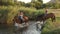 Two girls riding on horses bathe horses in lake.