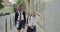 Two girls sisters going to school, children in school uniform with backpacks talking