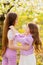 two girls sisters have fun and cuddle in the garden with flowering trees.