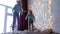 Two girls sisters jumping on bed at home in Christmas interior with garlands.