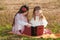 Two girls sisters read the book on the grass