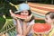 Two girls sit in a hammock and eat big red slices of watermelon