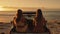 Two girls sitting on back of ute at beach