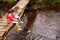 Two Girls Sitting On Bridge Fishing In Stream With Net