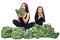 Two girls are sitting among broccoli, eating and drinking a green smoothie. vegan organic food concept