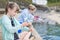 Two Girls Sitting On Harbour Wall Catching Crabs