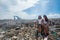 Two girls sitting among trash at garbage dump