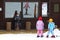 Two girls on skis watching a pretty smiling boy, who is sitting on a bench