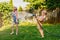 Two girls splashing each other with gardening house on backyard on summer day